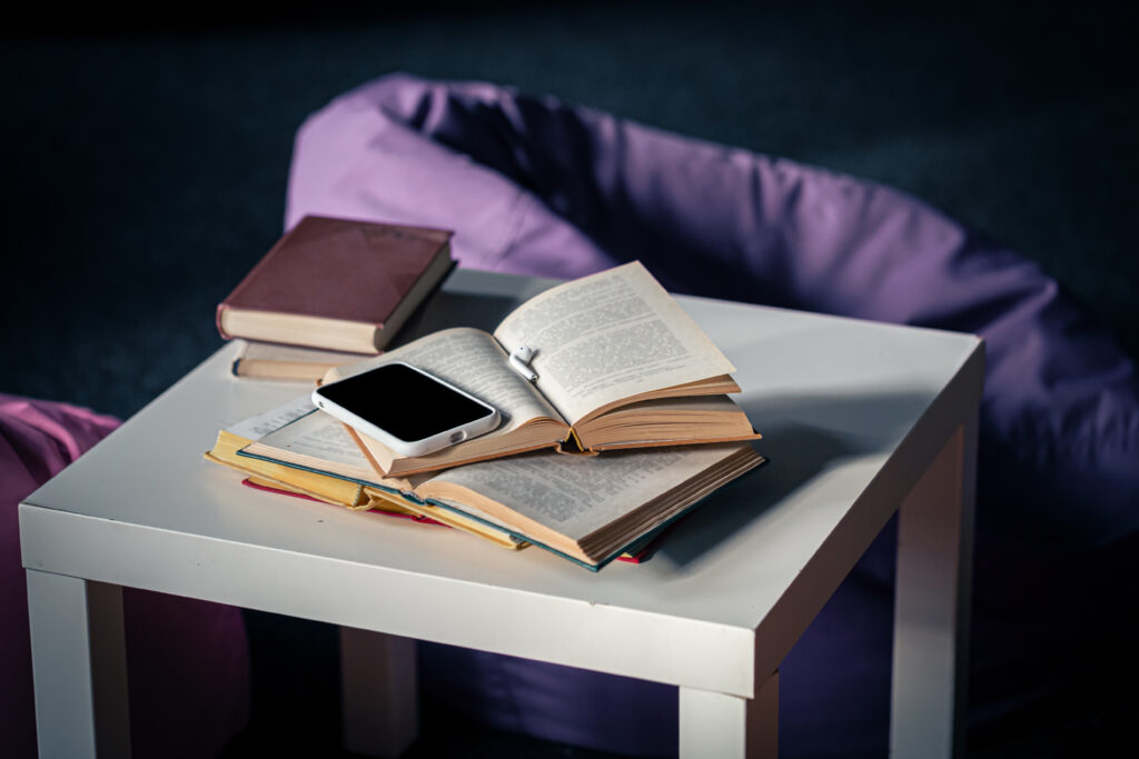 books on a small white table on a blurred background of the interior with poufs.
