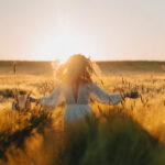 young beautiful woman with long blond hair in a white dress on a wheat field in the early morning at sunrise. Summer is the time for dreamers, flying hair, a woman running across the field in the rays of the sun. travels