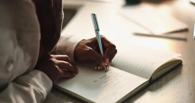 Close-up of hands journaling questions, representing honest doubt and wrestling with faith during deconstruction